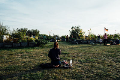 Boy sitting on field against sky