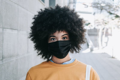 Portrait of young man standing against covering face