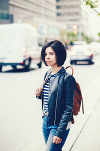 Side view of young woman standing on road in city