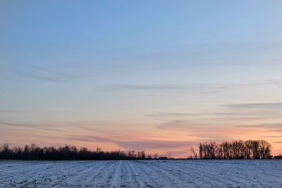 Scenic view of snowy field against sky during winter