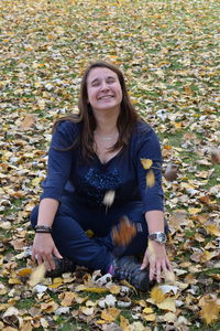 Portrait of smiling young woman sitting on autumn leaves