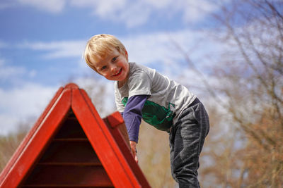 Low angle portrait of cute boy playing on outdoor play equipment