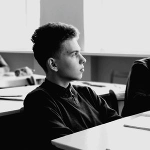 Young man sitting on bench in classroom