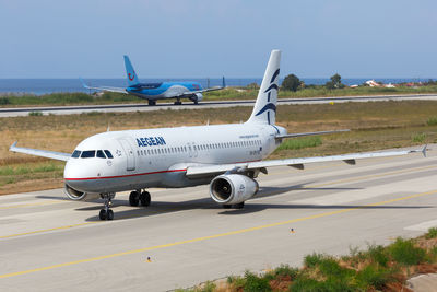 Airplane on airport runway against sky