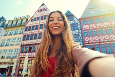 Portrait of smiling young woman against building