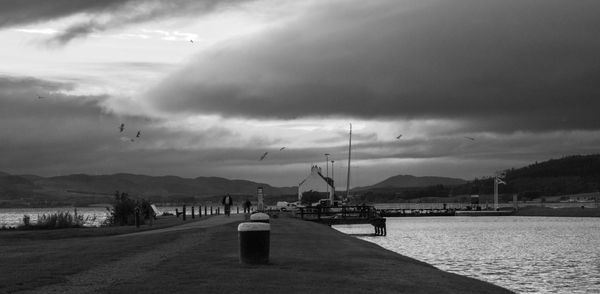 Pier by lake against cloudy sky