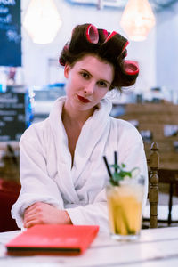 Portrait of young woman sitting at table in restaurant