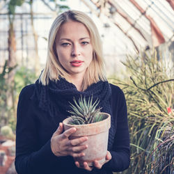 Portrait of young woman holding plant