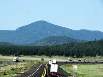 Cars on road by mountains against clear sky