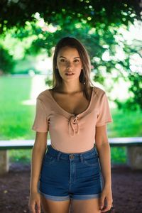 Portrait of beautiful young woman standing against trees