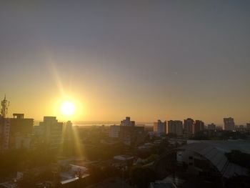 Buildings in city against clear sky during sunset