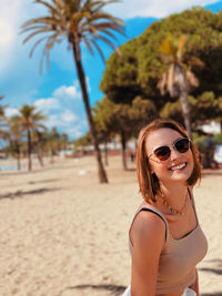Portrait of young woman wearing sunglasses standing at beach in marbella, andalusia. 