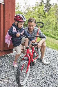 Father assisting daughter in riding bicycle