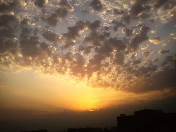 Low angle view of silhouette buildings against romantic sky at sunset