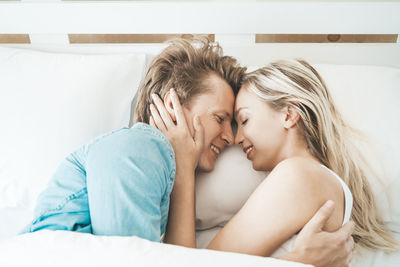 Couple cuddling on bed in home