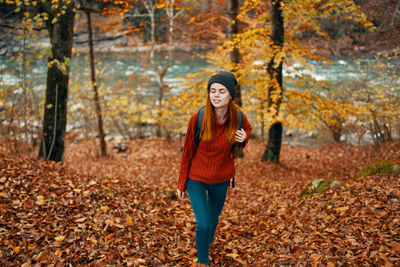 Full length of young woman in autumn leaves