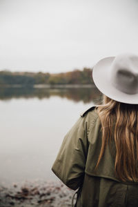 Rear view of woman standing by lake against sky