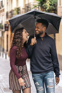 Midsection of man holding umbrella standing in rain