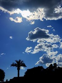 Low angle view of trees against cloudy sky