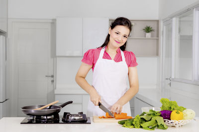 Portrait of woman preparing food in kitchen