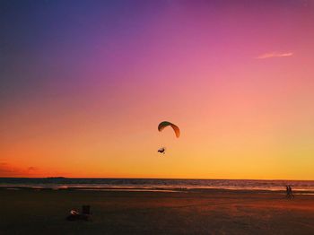 Scenic view of paraglider over sea at sunset 