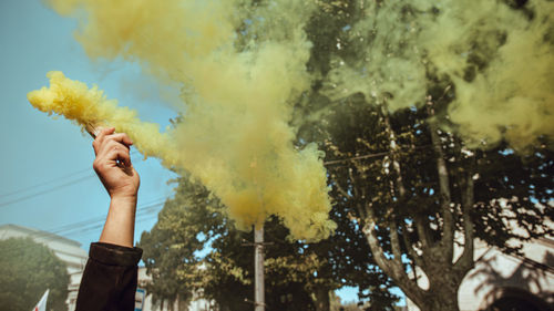 Cropped image of person holding distress flare against sky