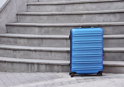 Blue luggage against steps in city