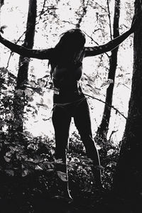 Rear view of woman standing in forest