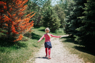 Full length of girl standing by tree in forest