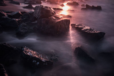 High angle view of rocks in sea during sunset