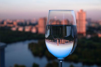 Close-up of wineglass against cityscape