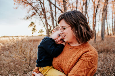 Happy mother hugging her content toddler on a warm autumn evening