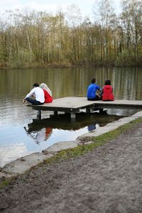 Rear view of men sitting on boat in lake