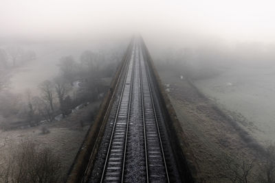 Aerial landscape above railway tracks on an old viaduct disappearing into the fog in the distance