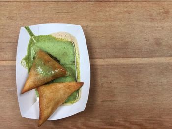 Close-up of samosas with sauce in plate on table