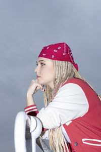 Blonde woman with dreadlocks and a red headscarf pensive