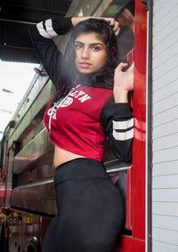 Portrait of young woman holding red while standing outdoors