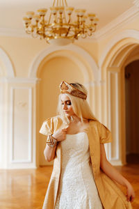 Young woman in dress standing against wall