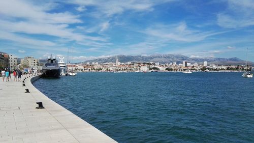 Promenade by sea against cityscape