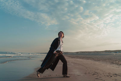 Young woman on beach against sky