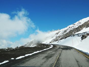 Road amidst snowcapped mountains against sky