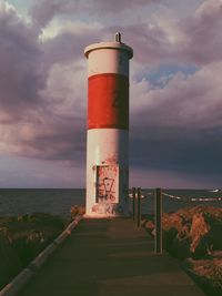 Lighthouse by sea against sky