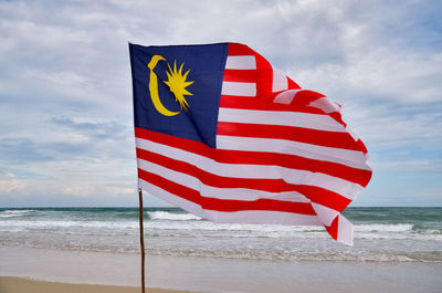Close-up of flag on beach against sky