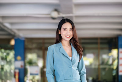 Portrait of young woman standing against building