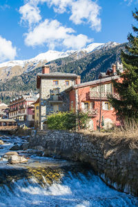 Bridge over river by buildings against sky