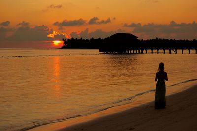 Silhouette woman standing at beach during sunset