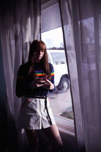 Woman photographing through window at home