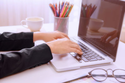 Close-up of person using laptop on table