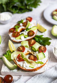 Bagels sandwich with cream cheese, cottage cheese, avocado, tomatoes, cucumbers and salad leaves