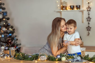 Mother embracing son while sitting at home